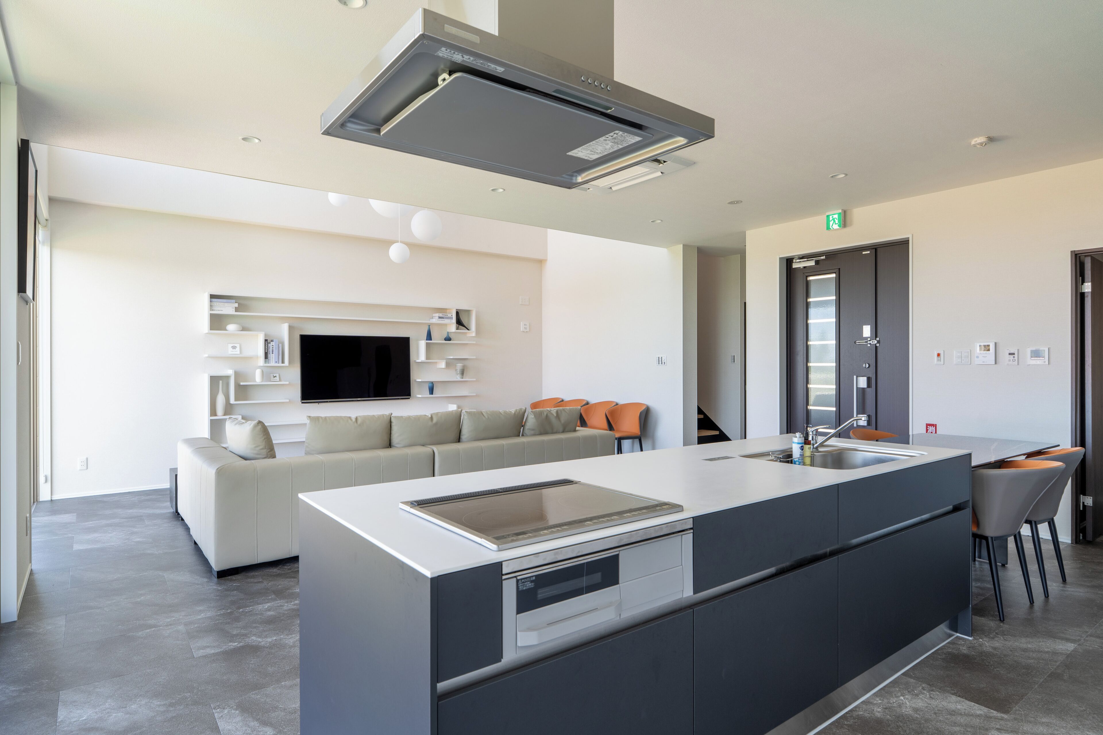 A modern kitchen with a central island, built-in oven, and a large overhead range hood.