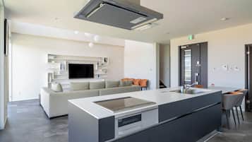 A modern kitchen with a central island, built-in oven, and a large overhead range hood.
