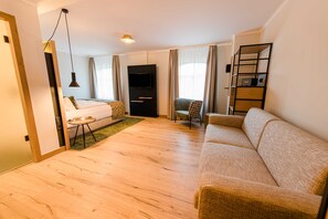 Una sala de estar moderna con un sofá, un sillón, un televisor y una estantería.