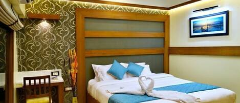 Habitación de hotel con cama, escritorio y silla. Cuenta con un ventilador de techo y un equipo de aire acondicionado.