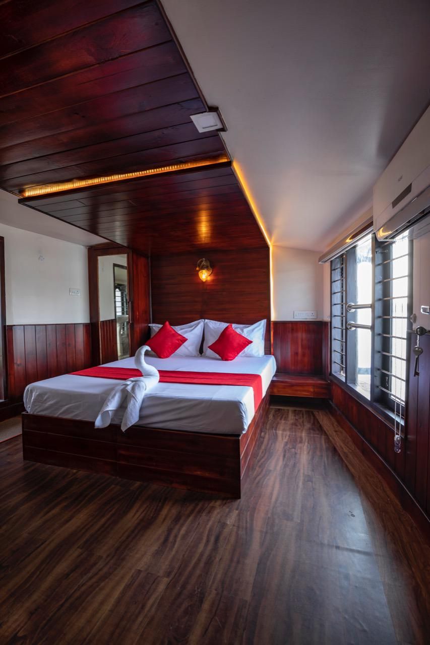 Una habitación con paneles de madera, una cama grande, almohadillas rojas y una toalla con forma de cisne.