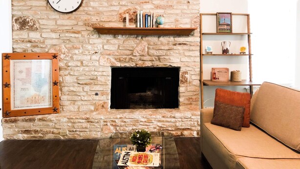 A living room with a stone fireplace, a clock, a bookshelf, and a sofa. - The Minimalism near FC Q2✌🏻5 mins to Domain ATX ❤️ (Austin)