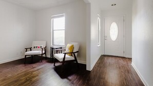 A room with hardwood flooring, two white chairs with cushions, a small round table, and a door with a frosted glass panel. - The Minimalism near FC Q2✌🏻5 mins to Domain ATX ❤️ (Austin)