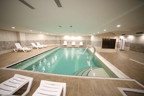 Una piscina techada, sillones reclinables de piscina