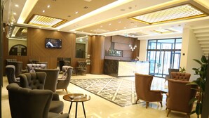 A lobby with plush seating, a reception desk, and a large screen. - Ema Ozturk Thermal Hotel (Afyonkarahisar)
