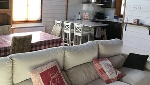 Un espace de vie chaleureux comprenant un canapé, une table à manger avec des chaises et un coin cuisine équipé d’une cuisinière et d’un four à micro-ondes.