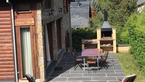 Une maison en pierre dotée d’un patio, d’un espace salon extérieur et d’un poêle à bois.