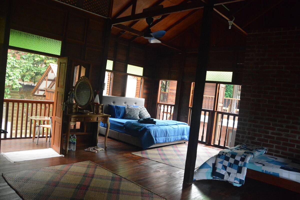 Una habitación amplia con una cama grande, un escritorio con silla, y vistas a un espacio exterior a través de una puerta.