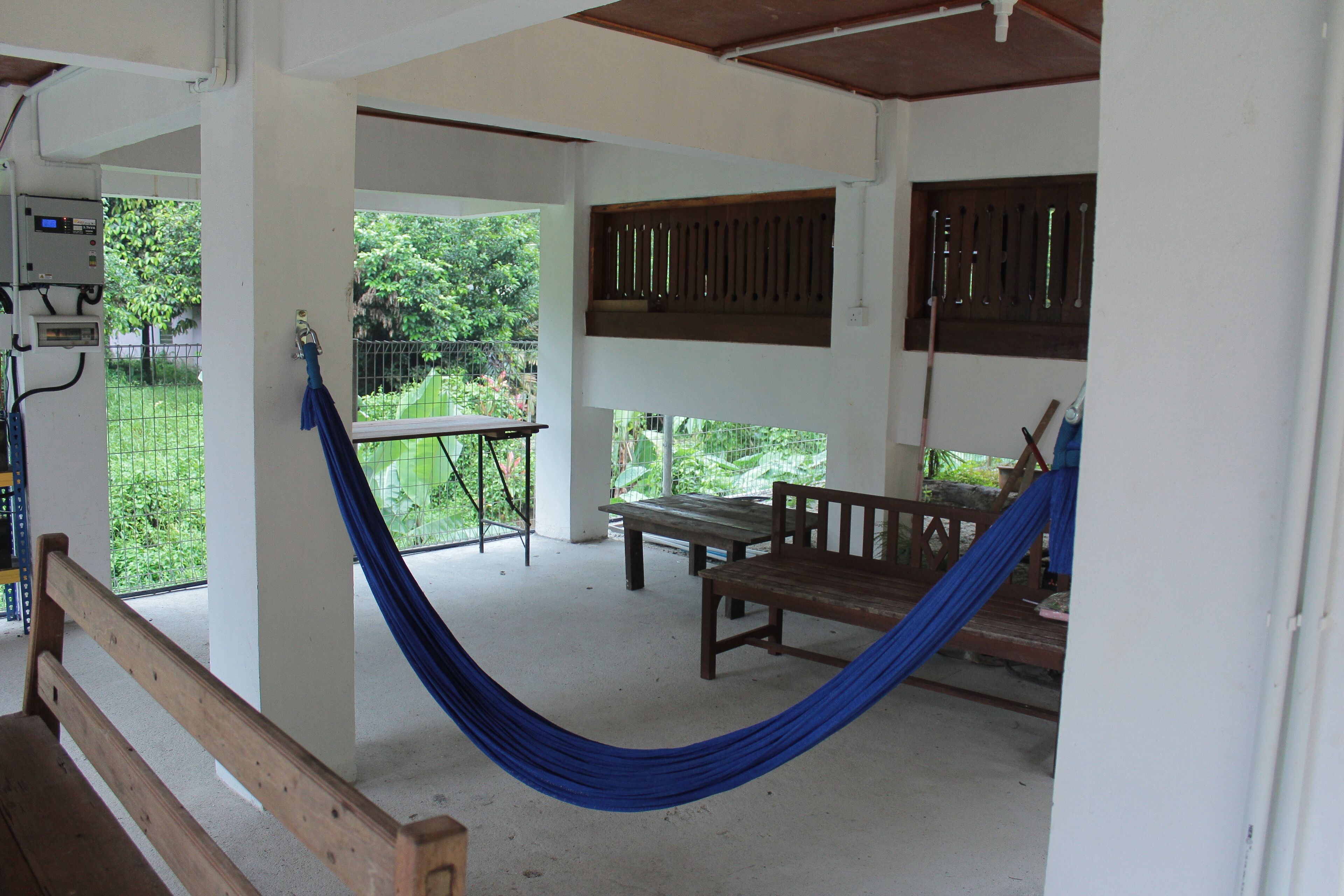 A room with a hammock, wooden bench, and a table.