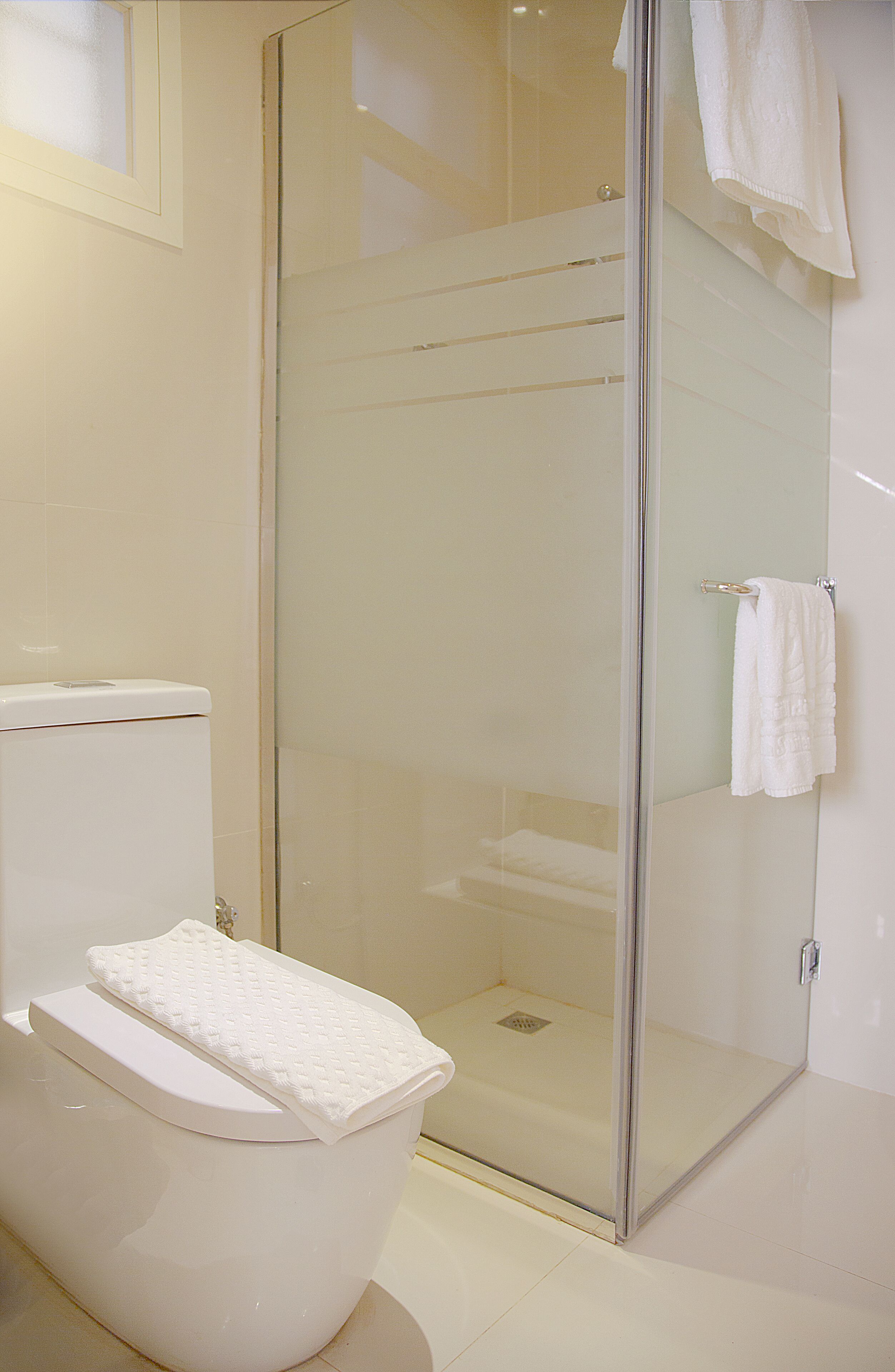 A bathroom with a toilet, a glass shower enclosure, and a towel hanging on the wall.
