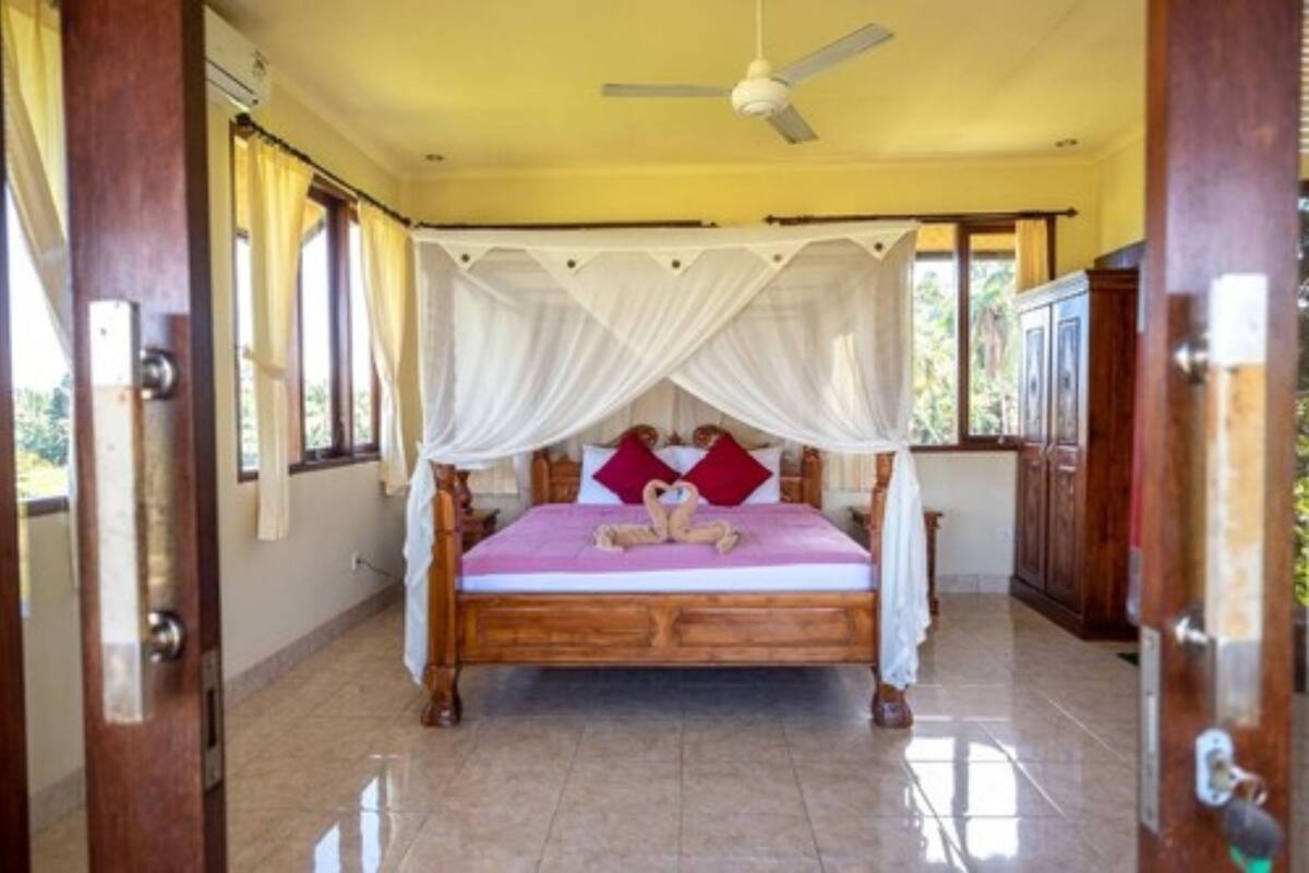 A bedroom with a wooden bed, white canopy, and a ceiling fan.