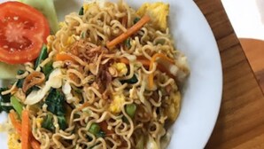 Due piatti di cibo, uno con noodles e verdure e l'altro con frutta.