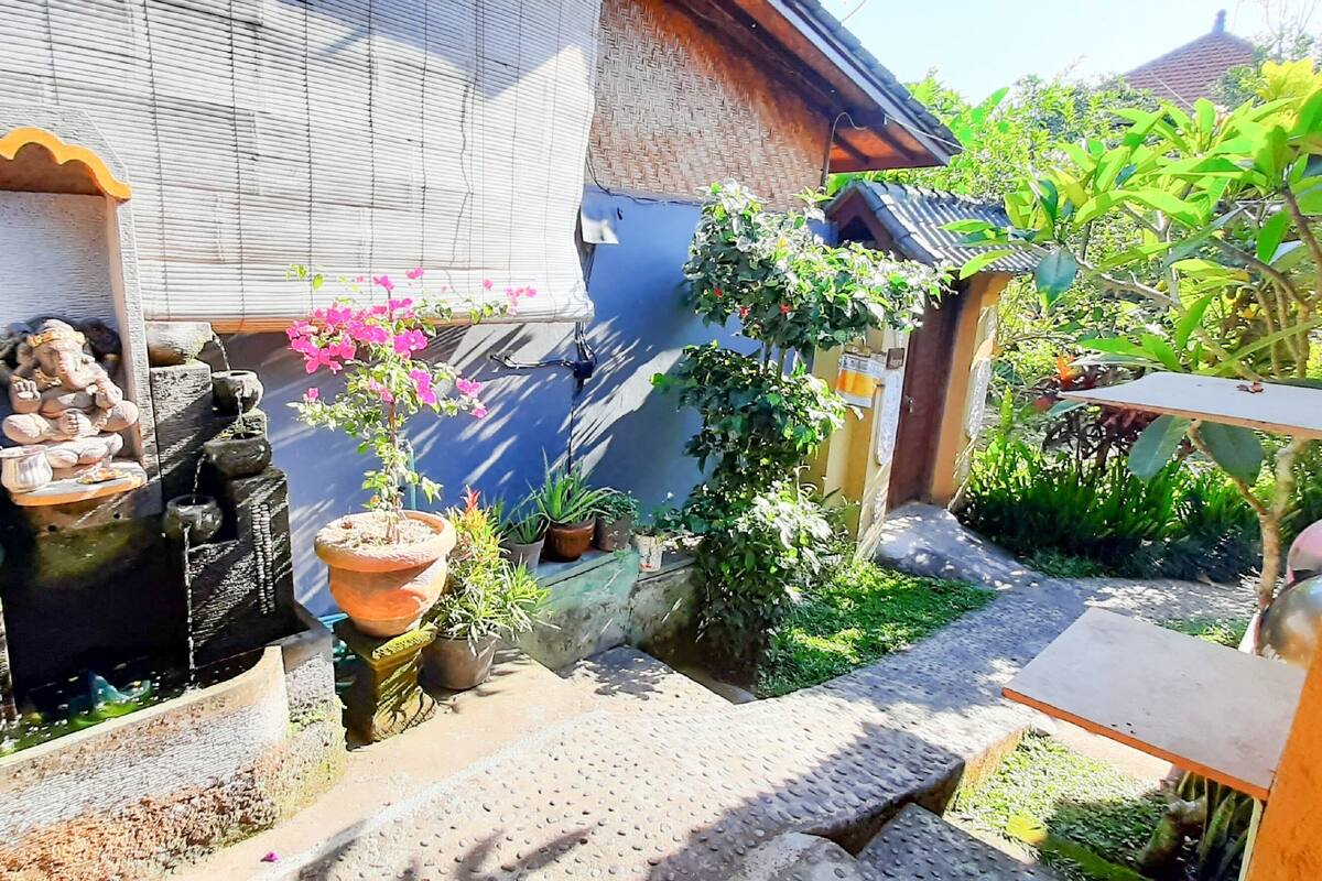 A courtyard with a water feature, potted plants, and a small statue.