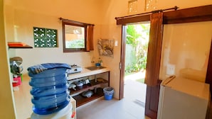 Una cucina compatta con lavandino, una finestra vista su del verde, e una porta che dà all'esterno.