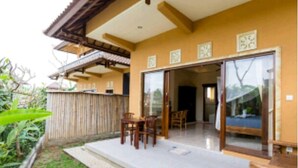 Una stanza con una porta a vetri scorrevoli che dà su un patio con tavolo e sedie in legno.