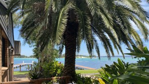 Une terrasse offrant une vue sur une mer paisible, une plateforme en bois et une végétation luxuriante.