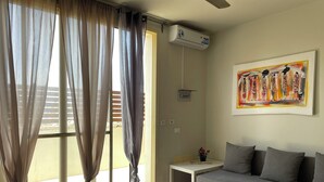 A living room with a grey sofa, a small table with a vase of flowers, and a painting on the wall. - Beautiful apartment 50 meters from the sea! (Sal Rei Boavista)