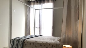 A bedroom with a bed, a bedside lamp, and a window with curtains. - Beautiful apartment 50 meters from the sea! (Sal Rei Boavista)