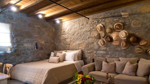 Una habitación acogedora con pared de piedra, cama, sofá y un perchero de pared.