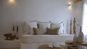 Un dormitorio con una cama, almohadas, una estatua de gato, mesitas de noche de madera y jarrones decorativos.