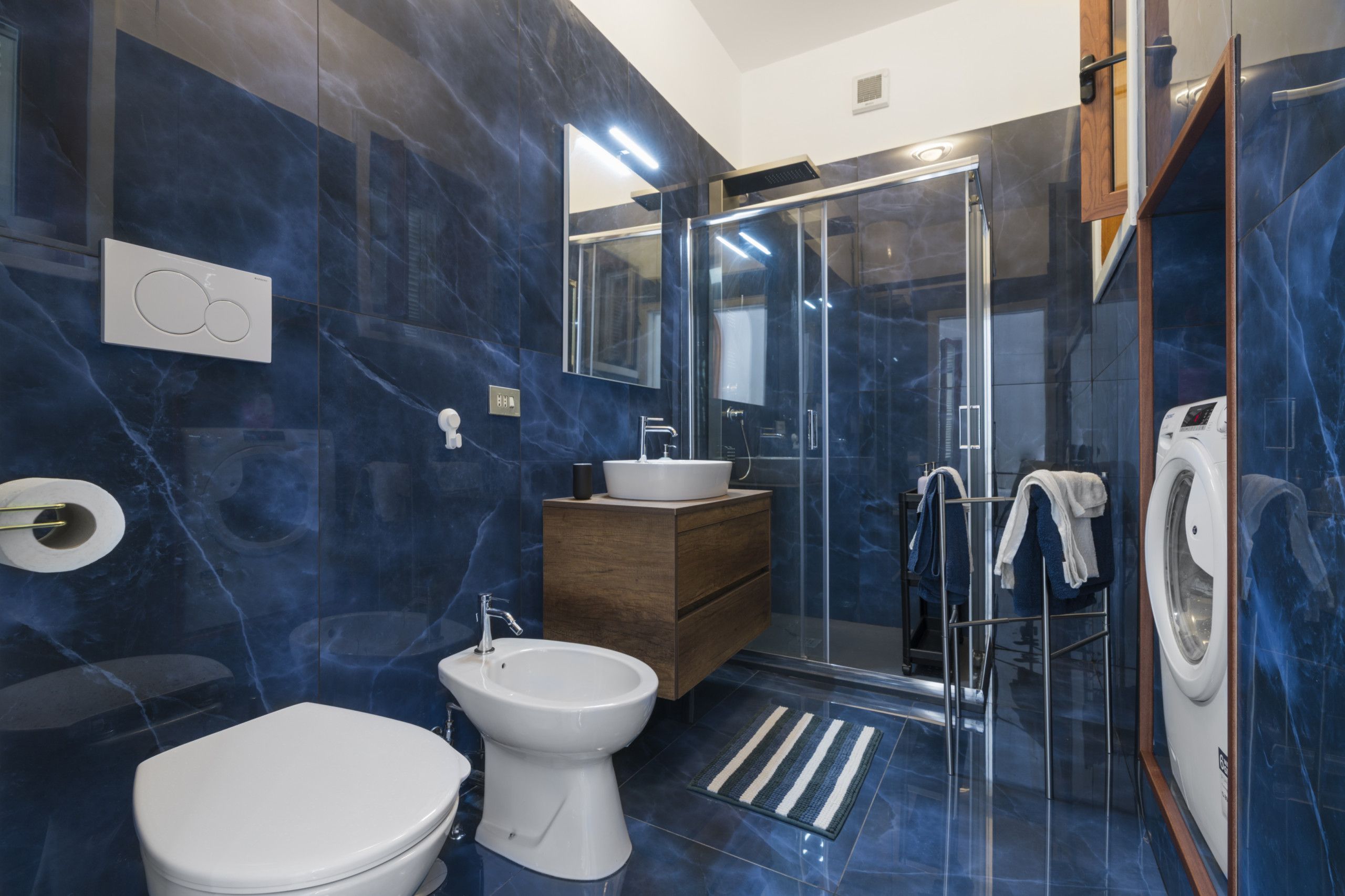 Een moderne badkamer met een toilet, wastafel, douchecabine van glas en een bidet.