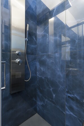 A modern bathroom with a glass-enclosed shower, marble walls, and a stainless steel shower control panel. - Villa Carrino (Positano)