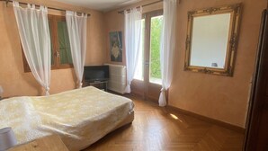 A room with a bed, a television, a radiator, and a window with curtains.