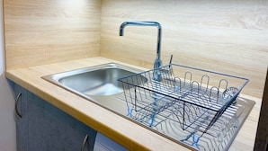Una cocina con un lavamanos de acero inoxidable, una encimera de madera y un escurreplatos.