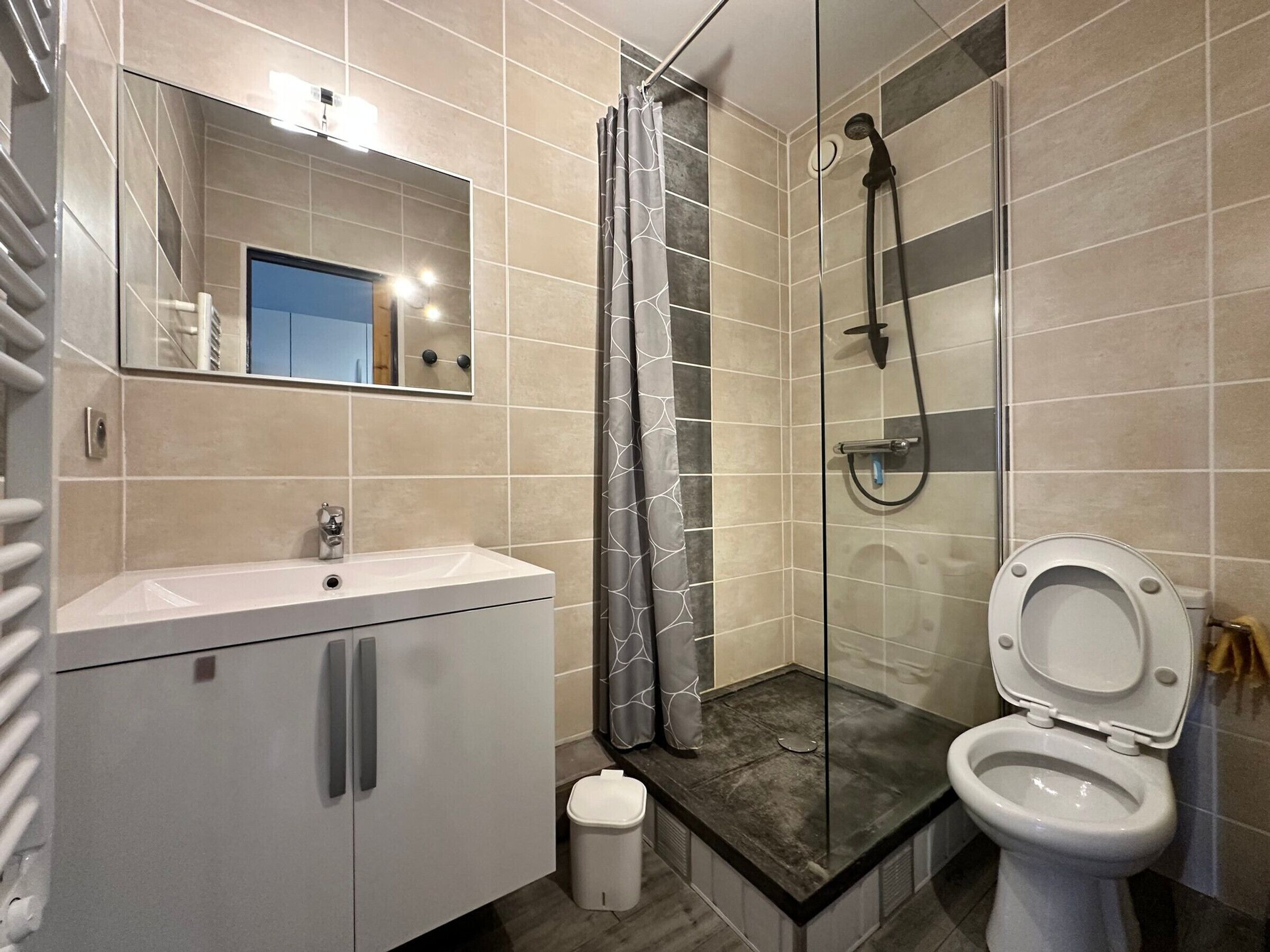 A modern bathroom with a shower, toilet, and sink.