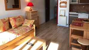 A cozy living room with a wooden sofa, a small table, a lamp, and a kitchen area with a microwave and cabinets. - Studio at the foot of slopes with balcony Corrençon-en-Vercors (Corrençon-en-Vercors)