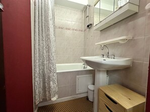 Ein Badezimmer mit einem weißen Waschbecken, einer Badewanne, einem Spiegel über dem Waschbecken und einer Duschvorhang mit Text.