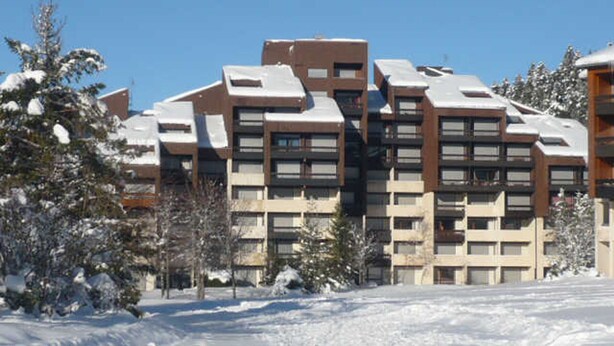Ein mehrstöckiges Gebäude mit modernem architektonischen Design, das eine Mischung aus rechteckigen und quadratischen Fenstern aufweist.