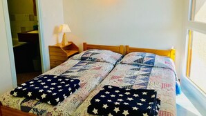 A bedroom with a wooden bed, a nightstand with a lamp, a wall-mounted light, and a painting. - 2-bedroom apartment at the foot of the slopes with balcony in Villard-de-Lans (Villard-de-Lans)