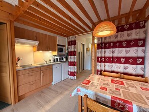Une cuisine compacte dotée de meubles en bois, d’un four à micro-ondes, d’un évier et d’un coin repas avec une table et des chaises.