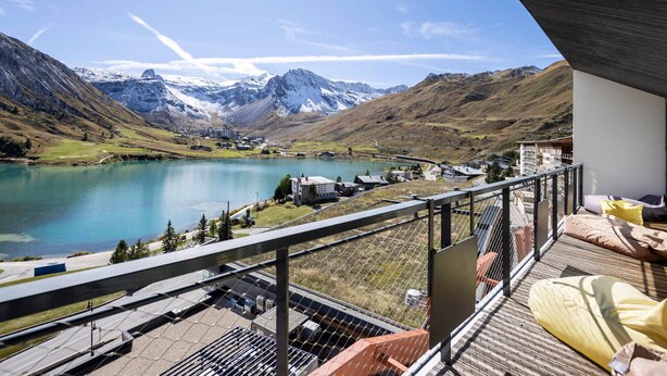 Un balcon avec vue sur un lac, des montagnes et une ville.