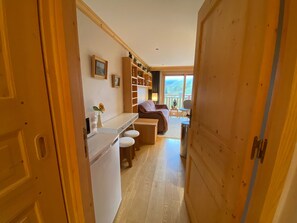 A compact living space with a kitchenette, a bed, and a view through a large window.