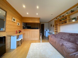A cozy cabin interior with a wooden dining area, a kitchenette, and a living space with a couch.