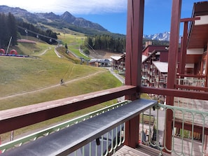 A mountain view with a ski lift, a wooden building with balconies, and a clear sky.