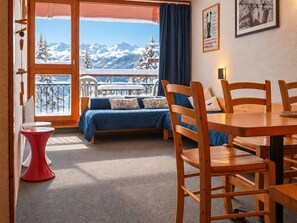 A cozy room with a bed, a dining table, and chairs. There's a view of snow-covered mountains through the window. - 2-room apt, 6 ppl, pets allowed, Arc 1800 (Les Arcs 1800)
