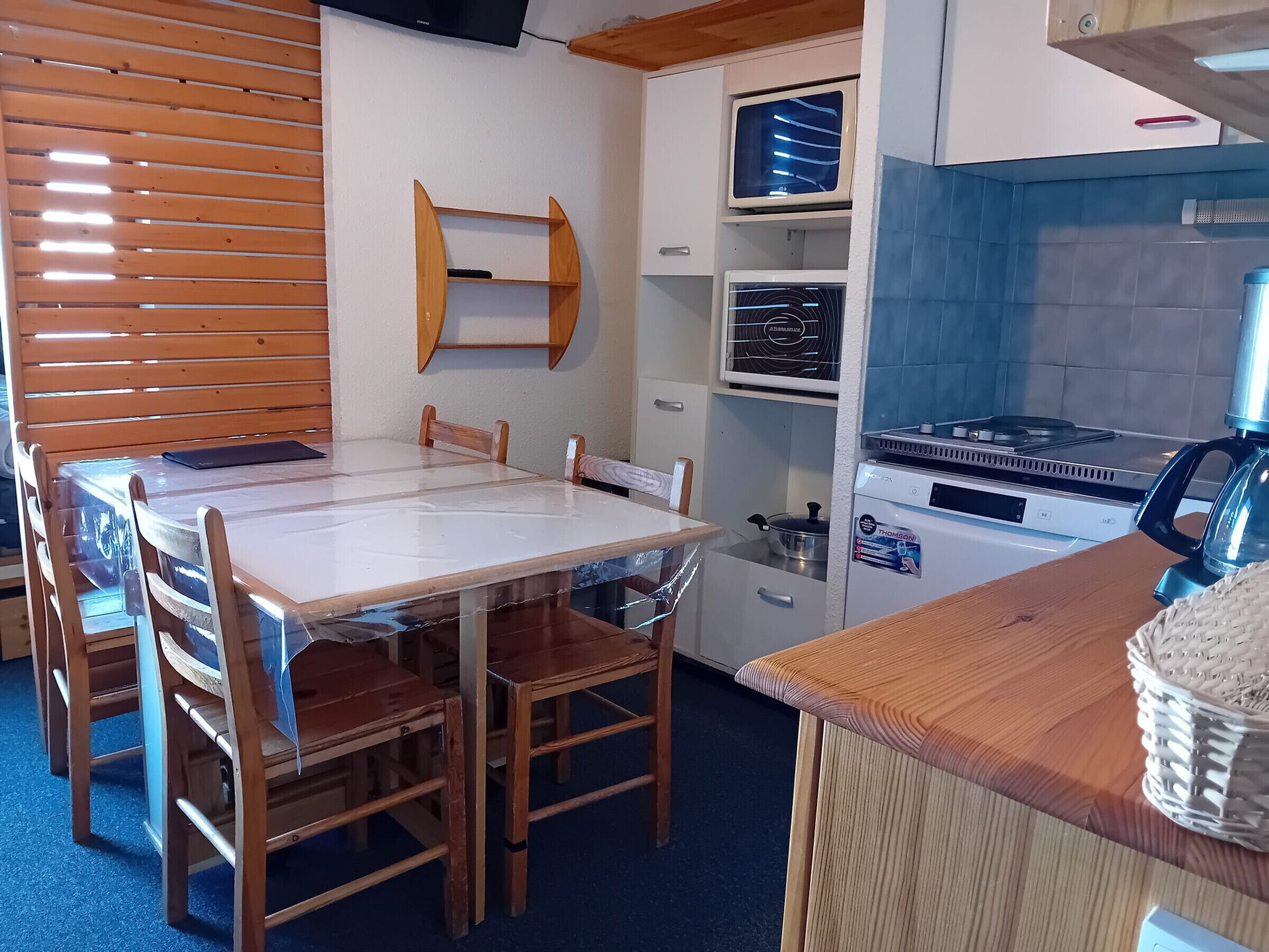 A compact kitchen with a wooden table and chairs, a built-in oven, a microwave, and a stove.