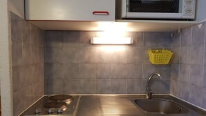 Een praktische keuken met een inbouwmagnetron, een gasfornuis en een spoelbak.