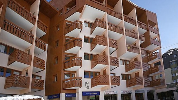 Ett hotell med flera våningar, balkonger och en klar himmel.
