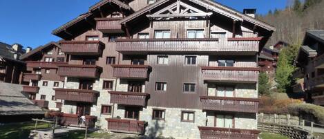 A multi-story hotel with wooden balconies and stone facade.