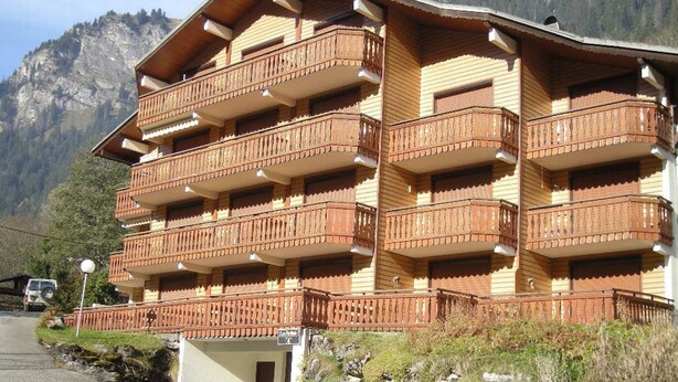 A multi-story hotel with balconies, set against a mountainous backdrop. - 6-person apartment with south-facing balcony and parking in Châtel (Châtel)