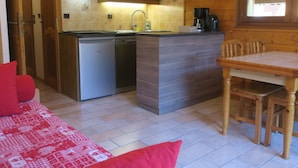 A compact kitchen with a microwave, dishwasher, and a small dining area with a wooden table and chairs. - 6-person apartment with south-facing balcony and parking in Châtel (Ch âtel)