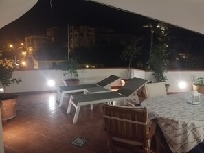 Une terrasse sur le toit, aménagée avec des chaises longues, une table et des plantes en pot.