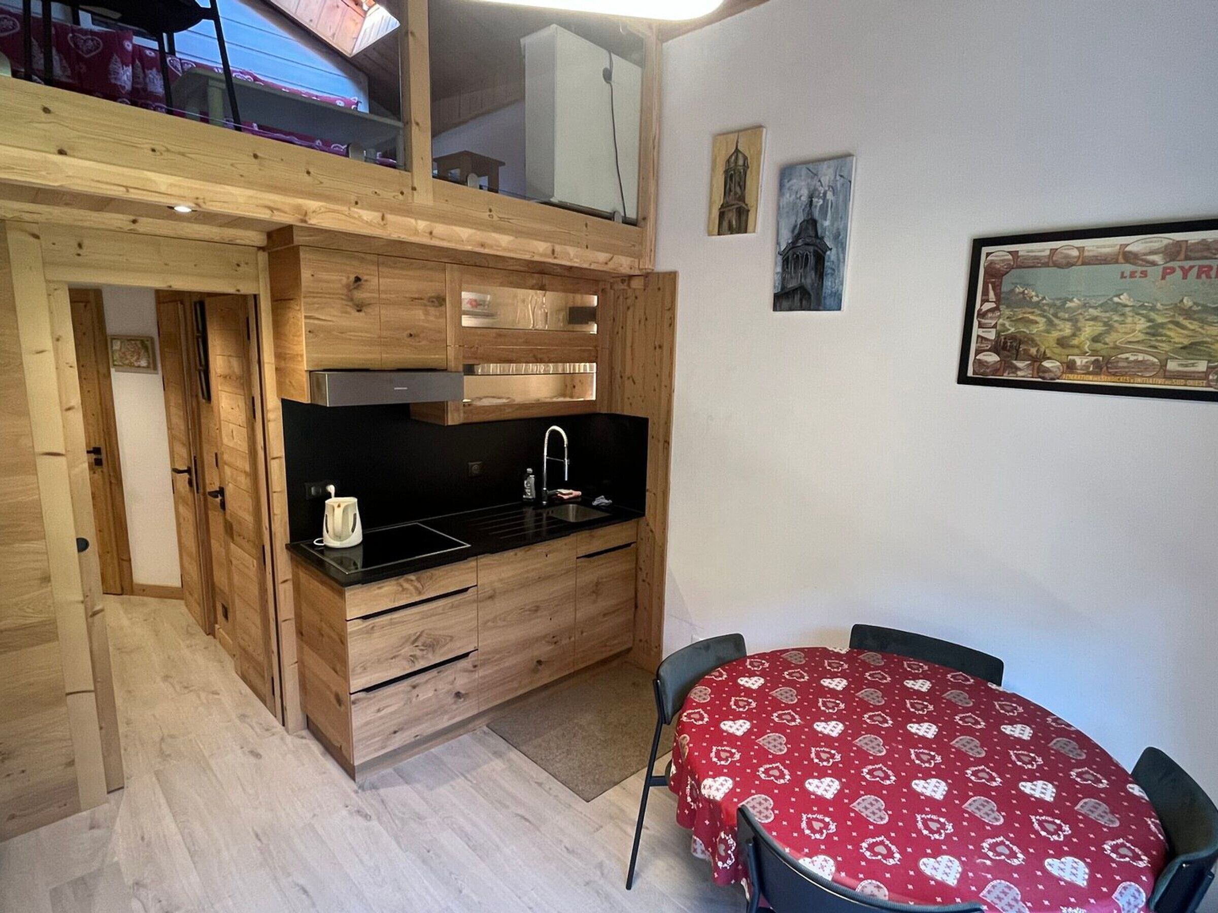 Eine kompakte Küche mit Holzschnitzereien, einer schwarzen Arbeitsplatte und einem Essbereich mit einer roten Tischdecke.