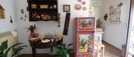 A cozy living room with a wooden table, a decorative wall shelf, and a colorful door.