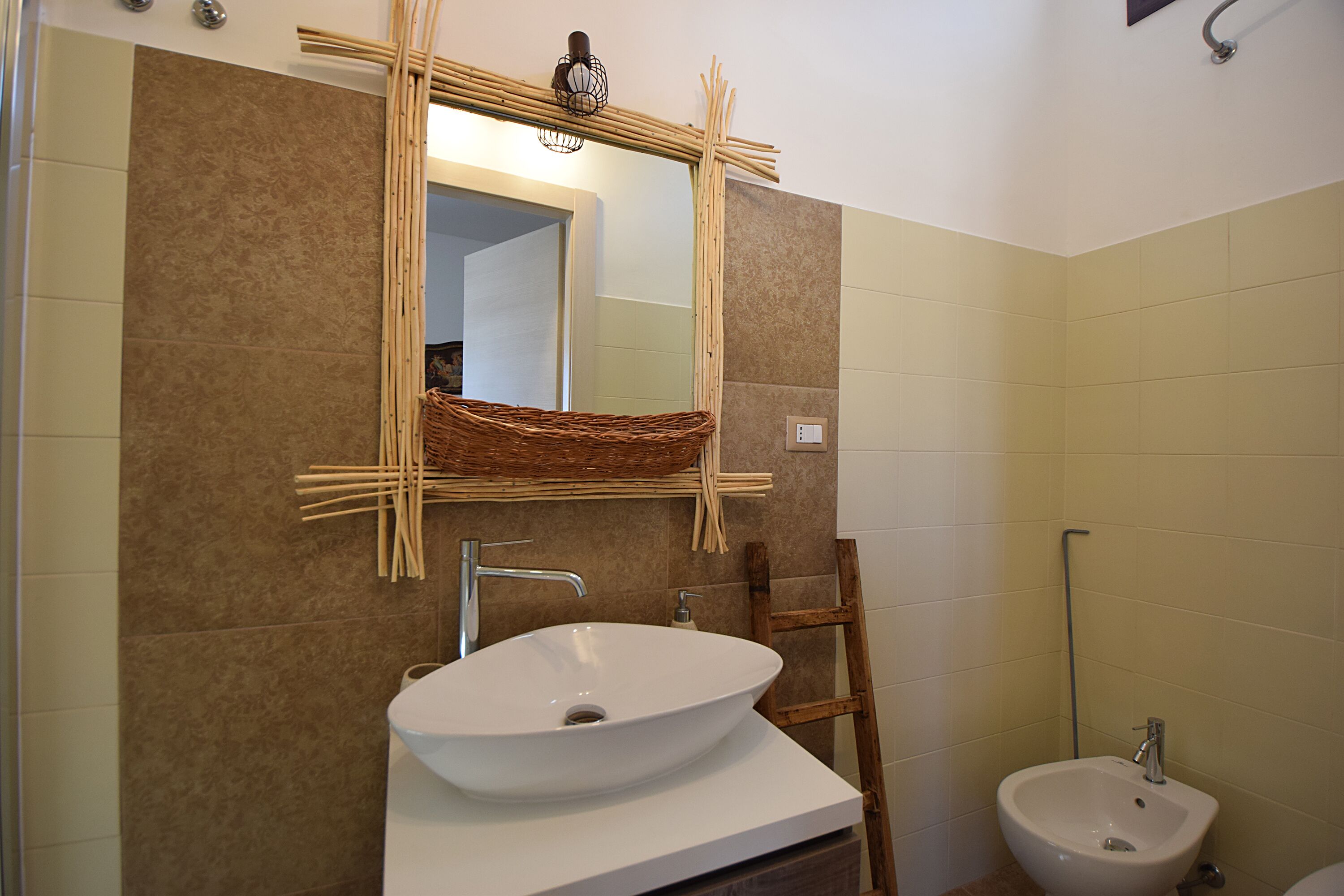 A bathroom with a white sink, a wooden chair, and a bidet.