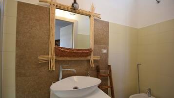 A bathroom with a white sink, a wooden chair, and a bidet.